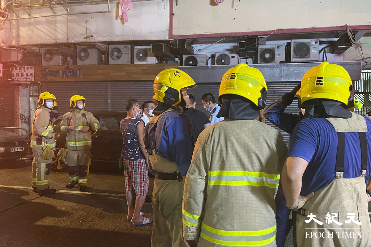 消防將火救熄後，於現場調查起火原因。警員向現場街坊了解事發經過。（卓相如／大紀元）