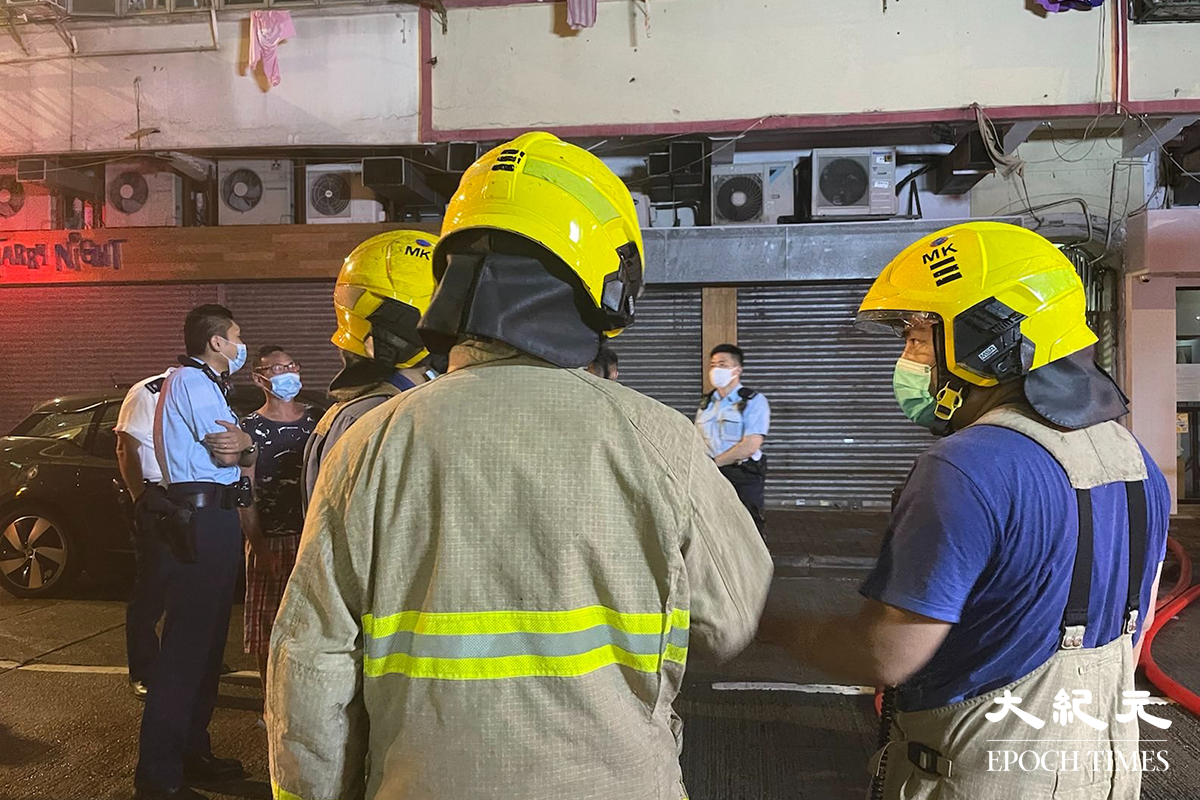 消防將火救熄後，於現場調查起火原因。警員向現場街坊了解事發經過。（卓相如／大紀元）