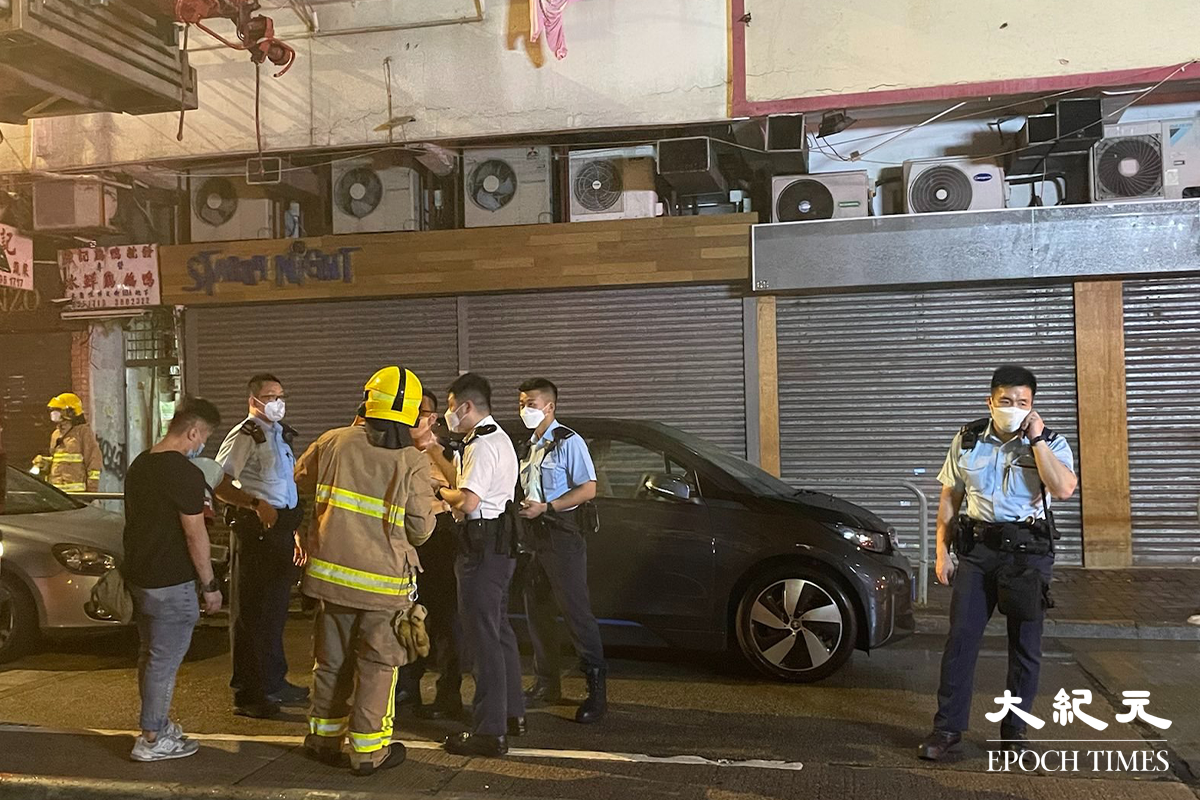 消防將火救熄後，於現場調查起火原因。警員向現場街坊了解事發經過。（卓相如／大紀元）