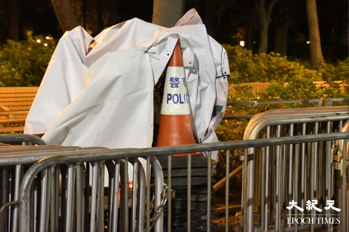 白色帆布下，擺放有數十個「警察」雪糕筒。（麥碧／大紀元）