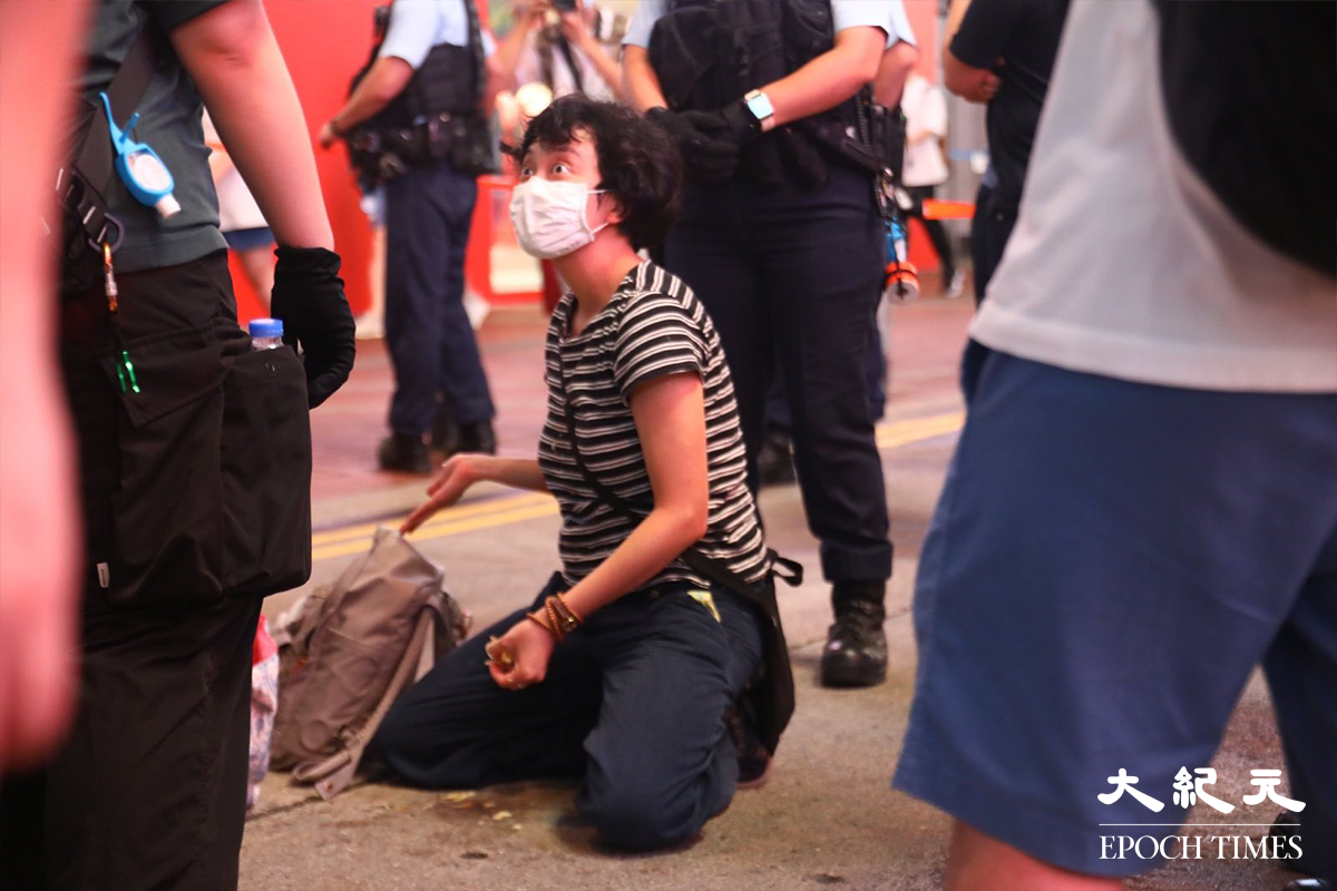 穿著間條衫的一位女行為藝術家，表演期間被多名警員喝止，並喝令清理地上的薯仔皮。其後，她被警員以涉嫌在公眾地方行為不檢罪名拘捕帶走。（胡琪／大紀元）