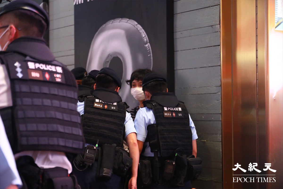 穿著間條衫的一位女行為藝術家，表演期間被多名警員喝止，並喝令清理地上的薯仔皮。其後，她被警員以涉嫌在公眾地方行為不檢罪名拘捕帶走。（胡琪／大紀元）
