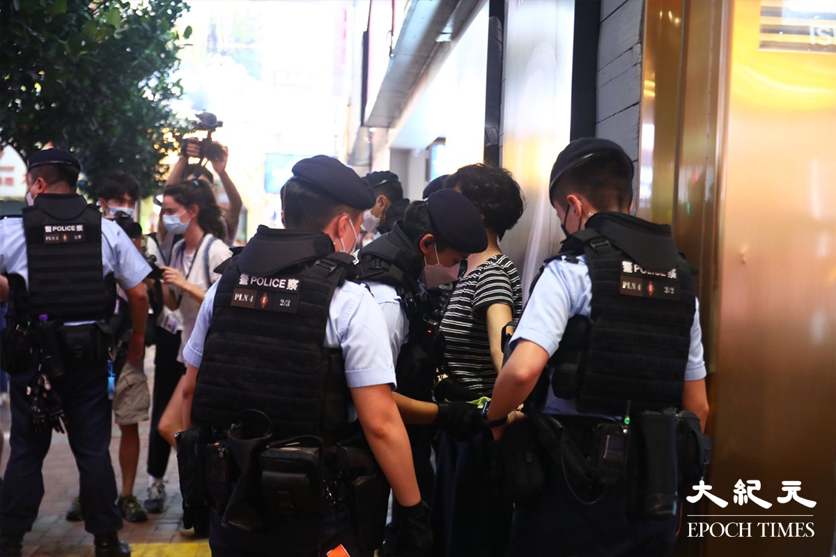 穿著間條衫的一位女行為藝術家，表演期間被多名警員喝止，並喝令清理地上的薯仔皮。其後，她被警員以涉嫌在公眾地方行為不檢罪名拘捕帶走。（胡琪／大紀元）