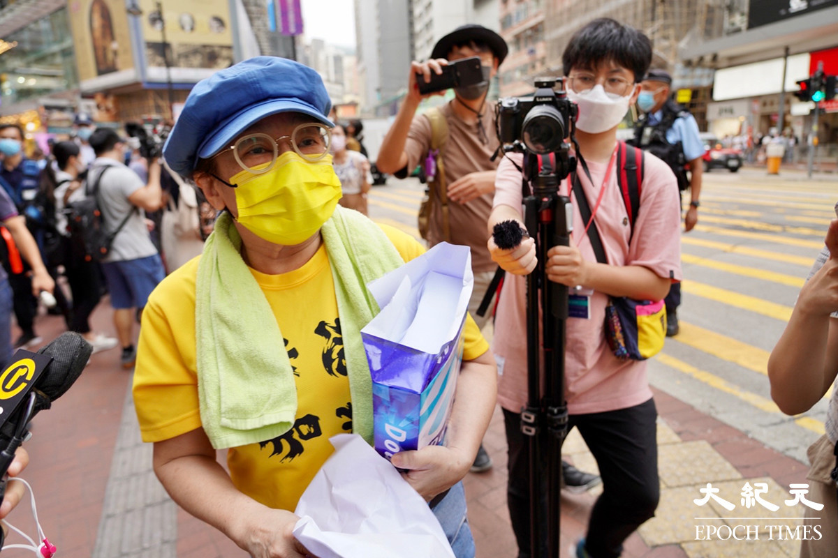 身穿寫有「香港加油」黃色上衣的盧女士在銅鑼灣派白紙。（余鋼／大紀元）