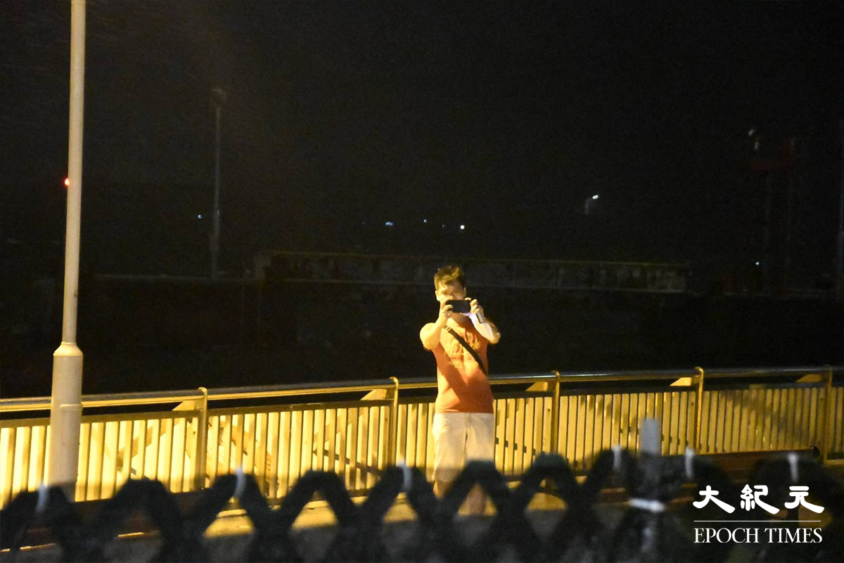 晚上約10時，杏花邨海濱長廊風勢相當大及雨勢頗密。有一名市民走到海邊打卡拍照，其後經在場民安隊員勸喻離開。（麥碧／大紀元）