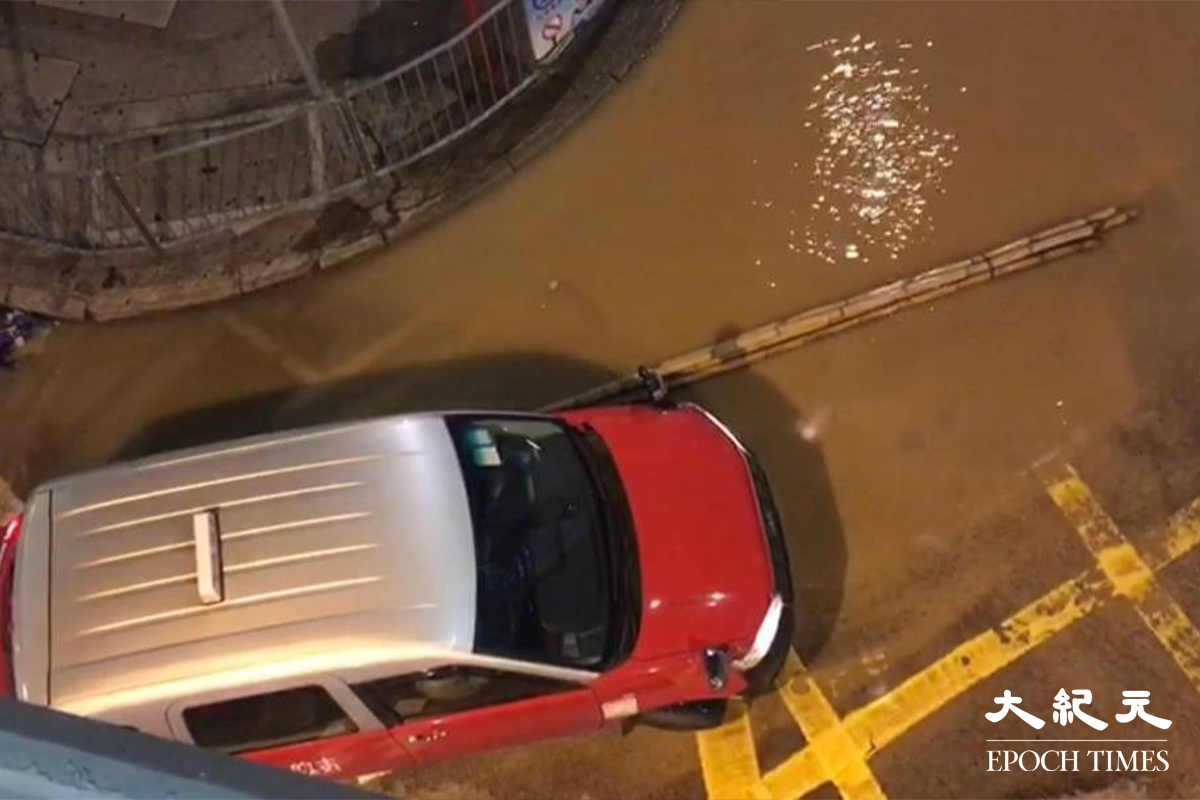 期間有數支搭棚用的竹支隨水漂到馬路上，多部車需要倒車離開。（佘實菁／大紀元）