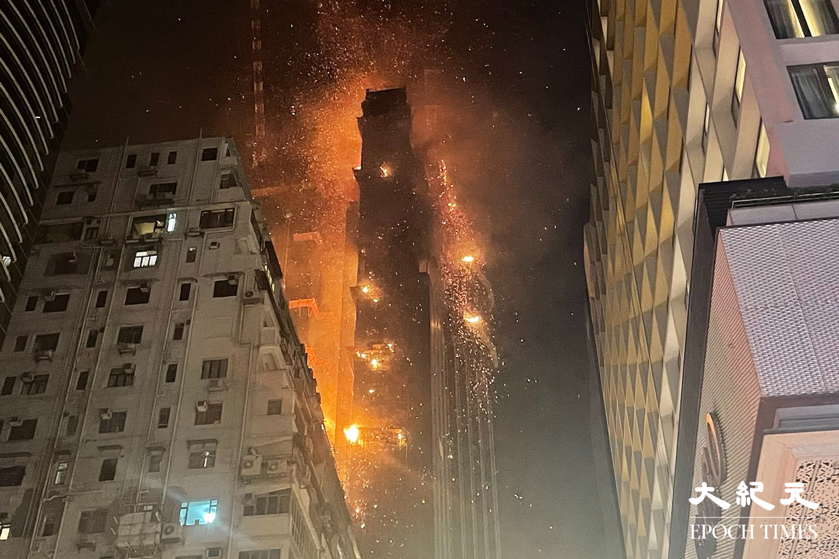 凌晨一時左右，現場火勢仍然相當猛烈，更不時傳出爆炸聲，火屑連同雜物不斷掉到街上。（卓相如／大紀元）