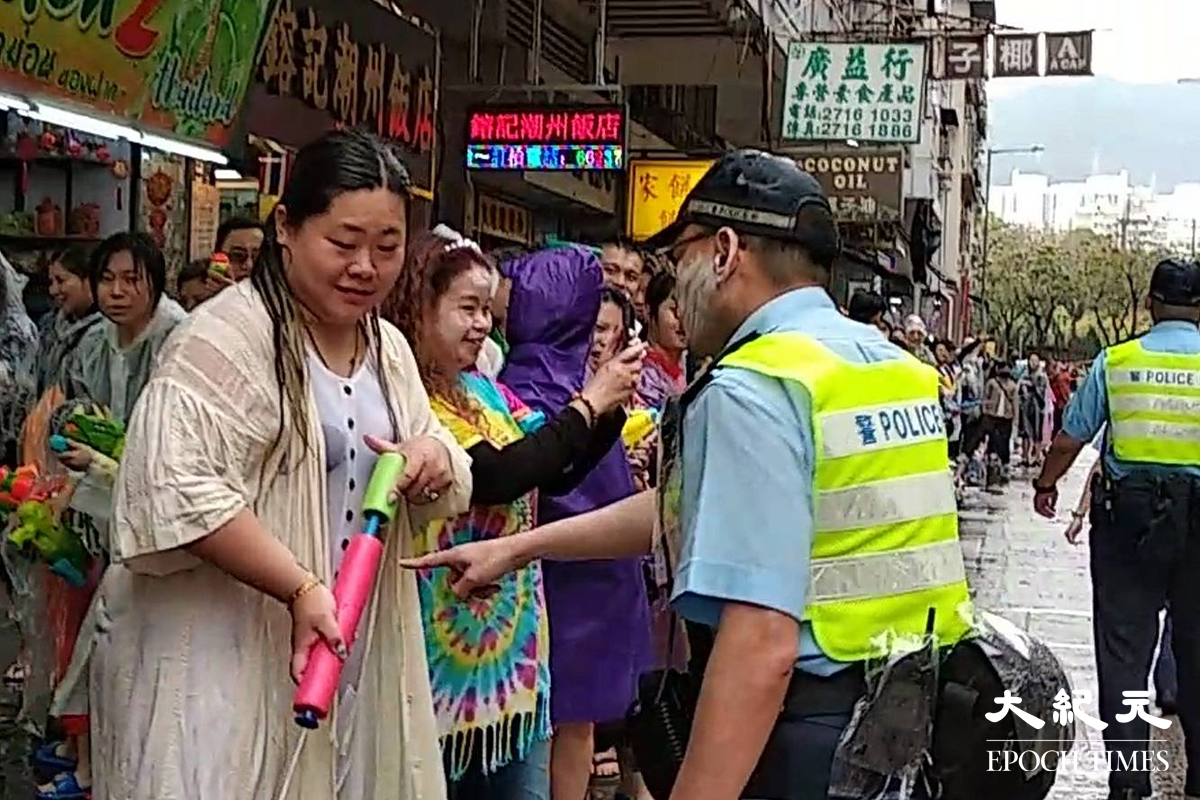 一名警員指著路邊一名女士稱，不要再向警察射水，該名女士一臉尷尬。 資料圖片（劉港業／大紀元）